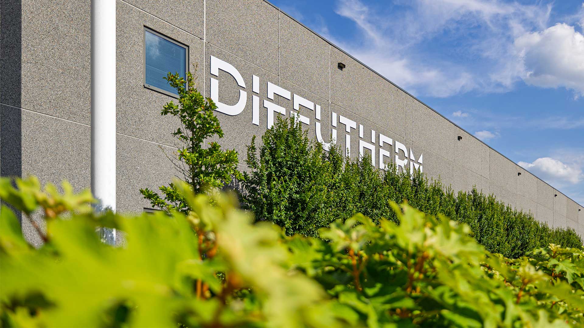 Exterior view of the Diffutherm company building with logo and greenery in the foreground.